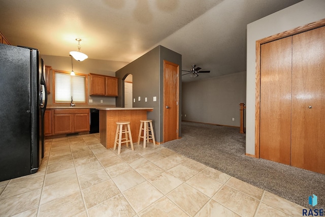 kitchen featuring black appliances, a kitchen island, decorative light fixtures, vaulted ceiling, and a breakfast bar