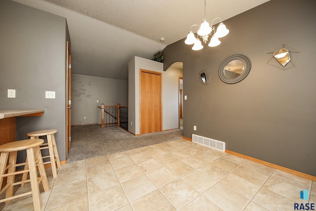 unfurnished dining area featuring light carpet, an inviting chandelier, and vaulted ceiling