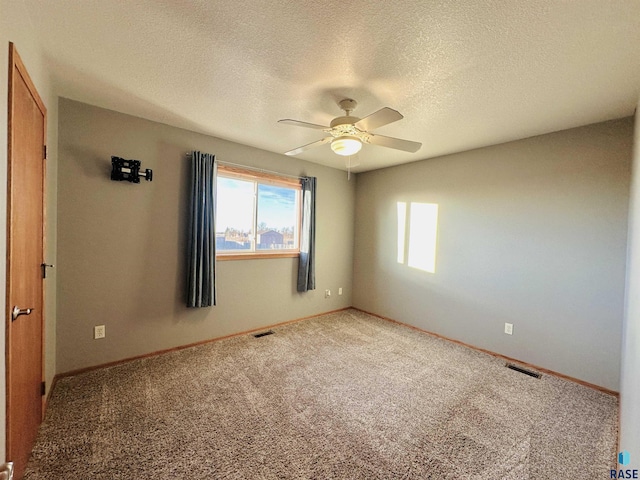 carpeted spare room with ceiling fan and a textured ceiling