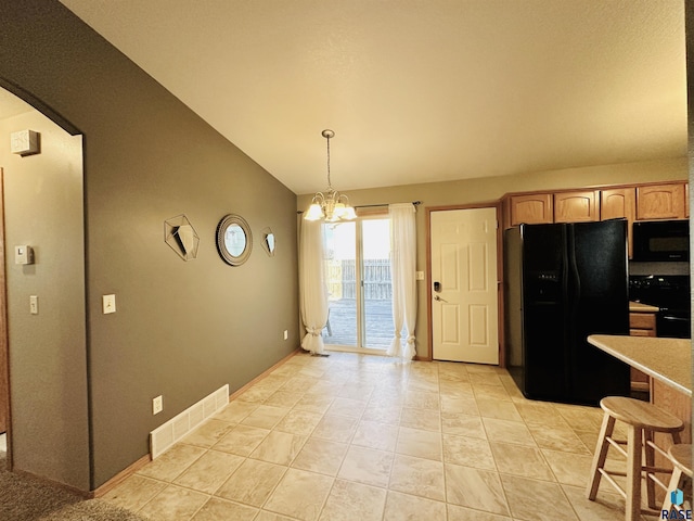 kitchen featuring vaulted ceiling, black appliances, hanging light fixtures, light tile patterned floors, and a chandelier