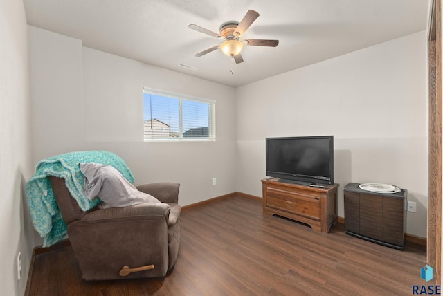 living area featuring dark wood-type flooring and ceiling fan