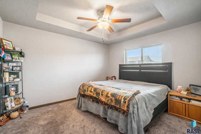 carpeted bedroom with ceiling fan and a tray ceiling