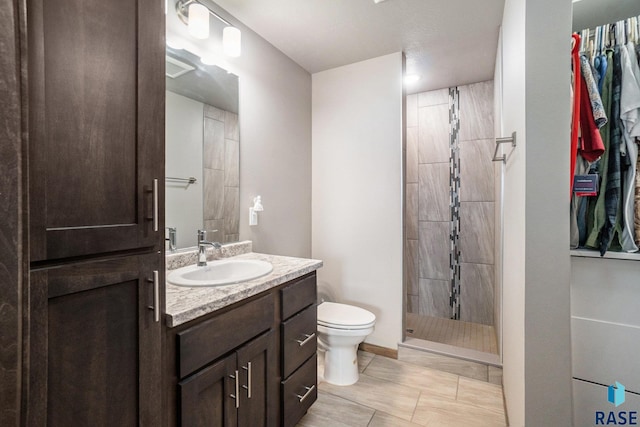 bathroom with toilet, vanity, and a tile shower