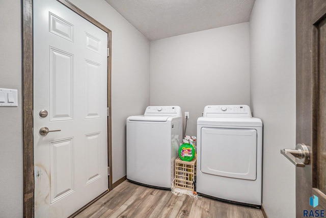 laundry room featuring light hardwood / wood-style flooring, washing machine and clothes dryer, and a textured ceiling