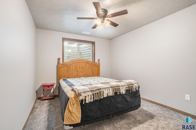 carpeted bedroom featuring ceiling fan and a textured ceiling