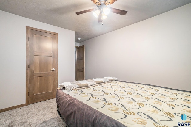 bedroom with ceiling fan, light colored carpet, and a textured ceiling