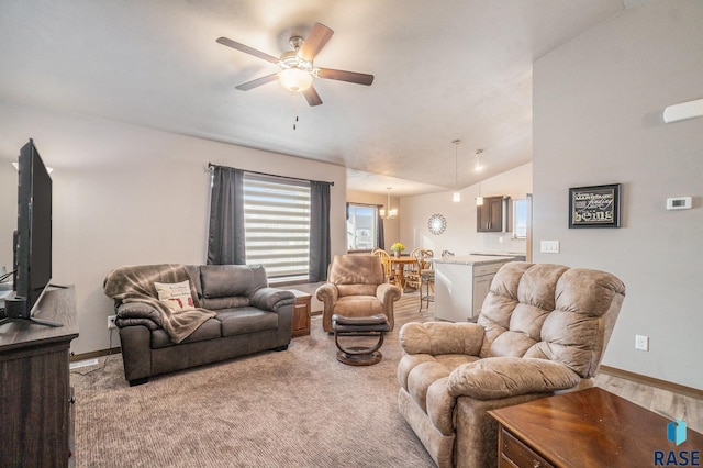 carpeted living room with ceiling fan with notable chandelier and vaulted ceiling