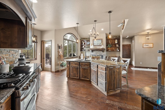 kitchen with gas range, tasteful backsplash, a center island, a textured ceiling, and a kitchen breakfast bar