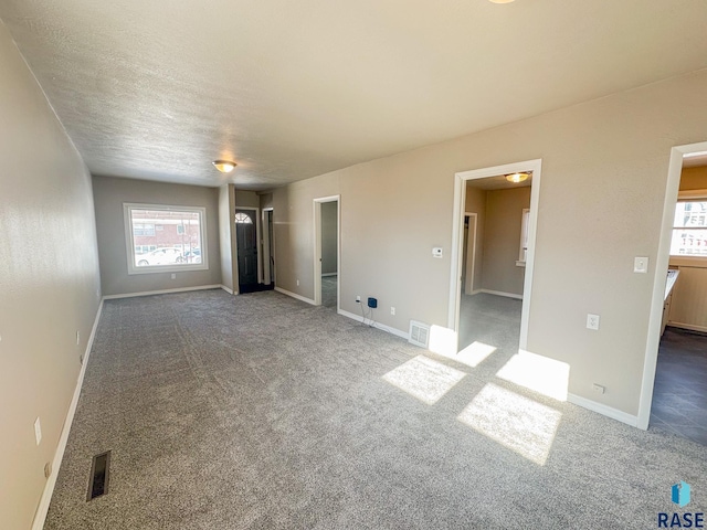 interior space featuring a textured ceiling and dark colored carpet