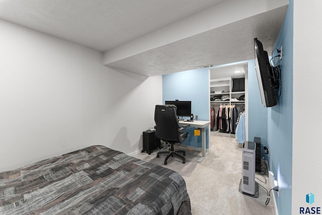 carpeted bedroom featuring a textured ceiling, a closet, and a walk in closet