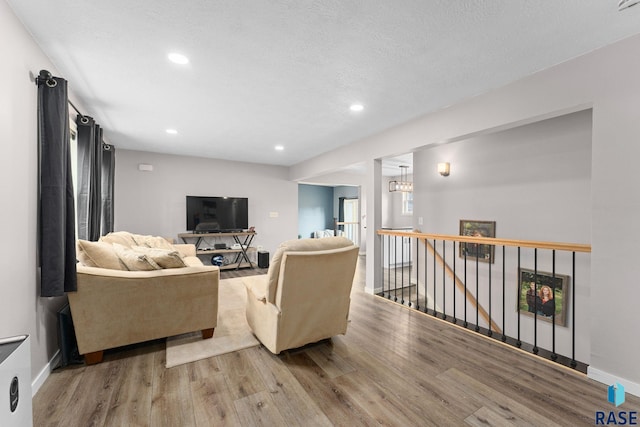 living room with a textured ceiling, a chandelier, and wood-type flooring