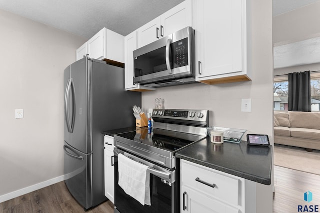 kitchen featuring a textured ceiling, dark hardwood / wood-style floors, stainless steel appliances, and white cabinetry