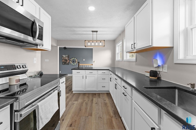 kitchen featuring appliances with stainless steel finishes, white cabinetry, sink, hanging light fixtures, and ceiling fan