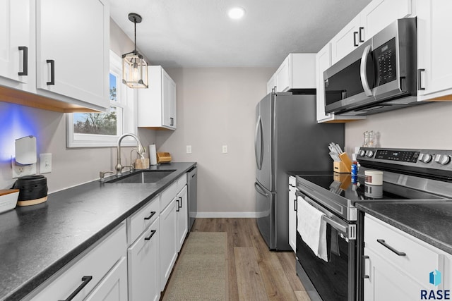 kitchen with light hardwood / wood-style floors, sink, hanging light fixtures, stainless steel appliances, and white cabinets