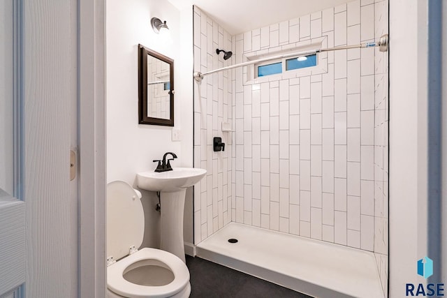 bathroom featuring toilet, sink, and a tile shower