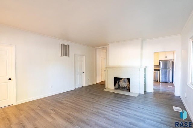 unfurnished living room featuring a fireplace, ornamental molding, and hardwood / wood-style flooring