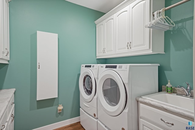 clothes washing area with cabinets, independent washer and dryer, wood-type flooring, and sink