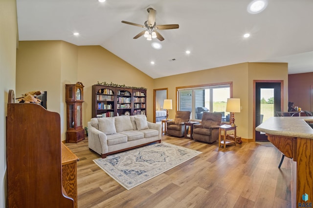 living room featuring ceiling fan, light hardwood / wood-style flooring, and vaulted ceiling