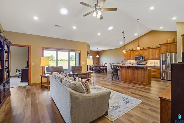 living room featuring light wood-type flooring, ceiling fan, and high vaulted ceiling