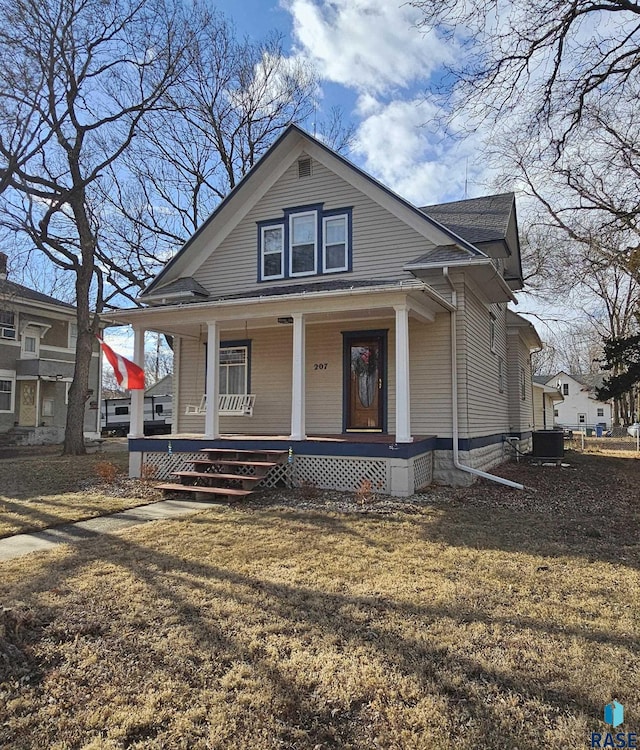 view of front of house with covered porch, a front lawn, and central AC unit