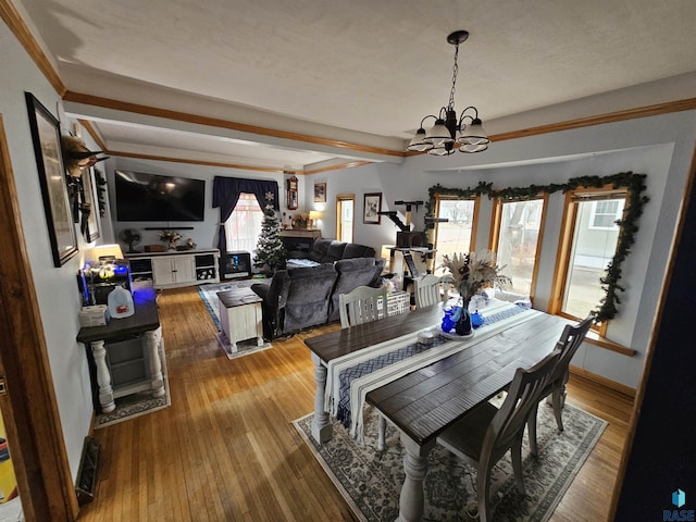 dining area with hardwood / wood-style flooring, beamed ceiling, a notable chandelier, and a healthy amount of sunlight