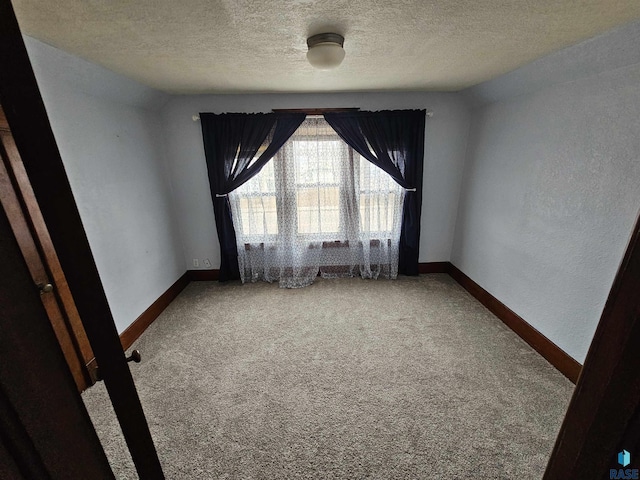 unfurnished room with a textured ceiling and carpet flooring