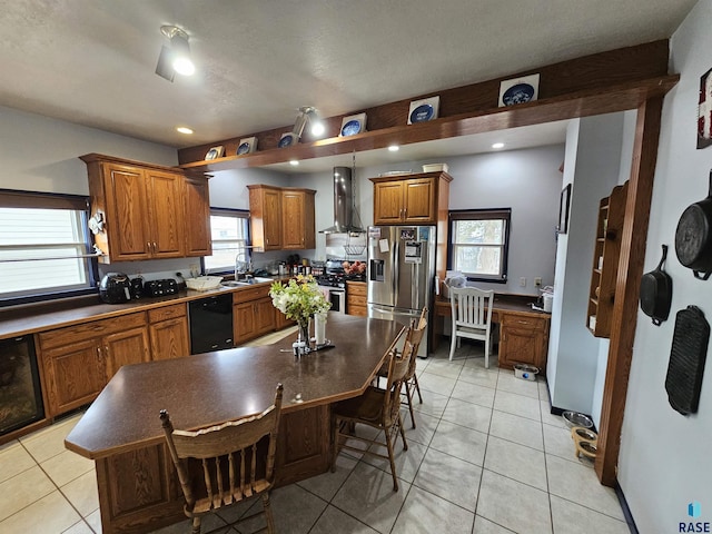 kitchen featuring wall chimney range hood, a kitchen island, appliances with stainless steel finishes, a breakfast bar area, and light tile patterned floors