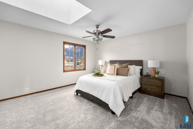 bedroom with carpet floors, a skylight, a ceiling fan, and baseboards