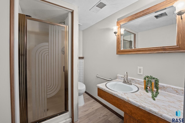 full bath featuring a stall shower, visible vents, toilet, and wood finished floors