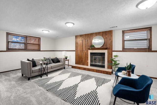 carpeted living area with a textured ceiling, a tiled fireplace, and visible vents