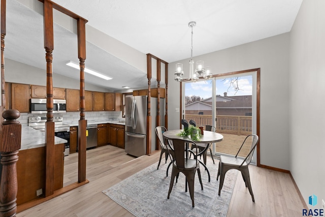 dining space with lofted ceiling, light wood-type flooring, a chandelier, and baseboards