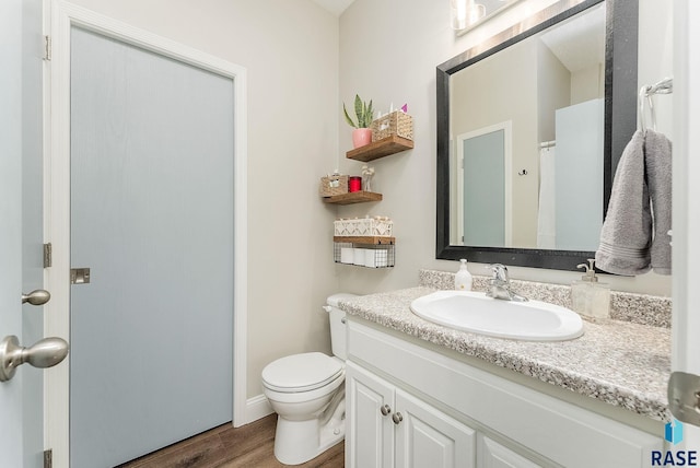 bathroom with toilet, vanity, and hardwood / wood-style floors