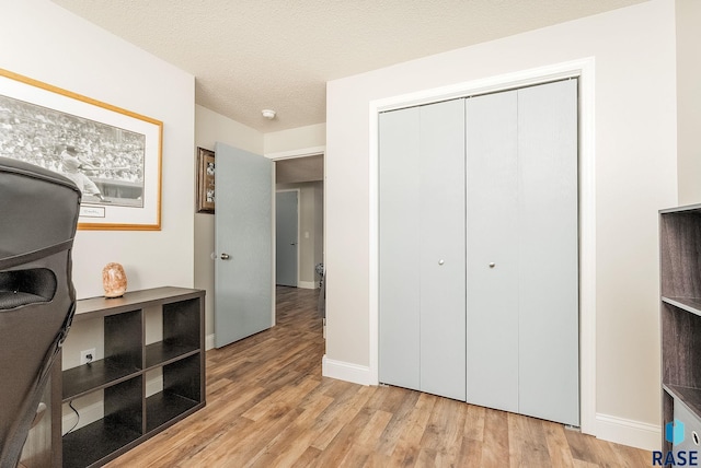 bedroom with a textured ceiling, a closet, and light wood-type flooring