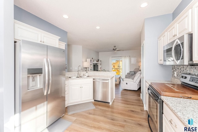 kitchen featuring tasteful backsplash, ceiling fan, sink, white cabinetry, and stainless steel appliances