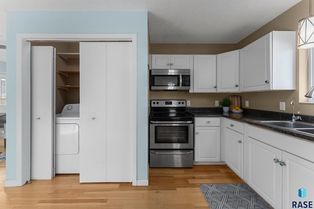 kitchen with white cabinets, washer / clothes dryer, appliances with stainless steel finishes, and sink