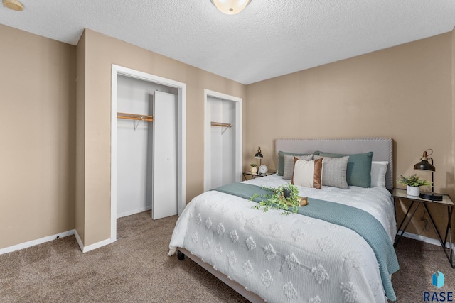 carpeted bedroom featuring two closets and a textured ceiling