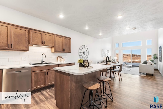 kitchen featuring a center island, dishwasher, sink, dark hardwood / wood-style floors, and a breakfast bar