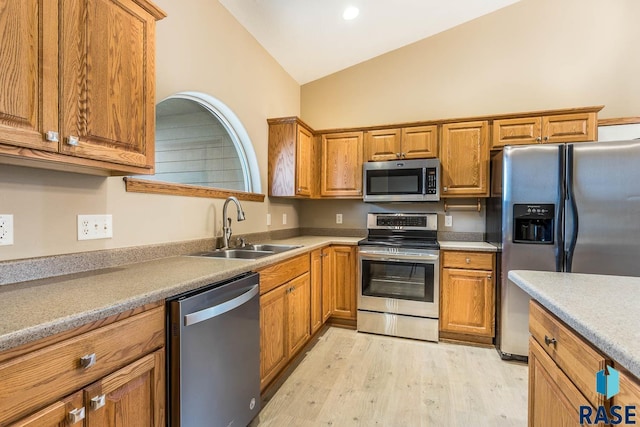 kitchen featuring vaulted ceiling, stainless steel appliances, light wood-type flooring, and sink