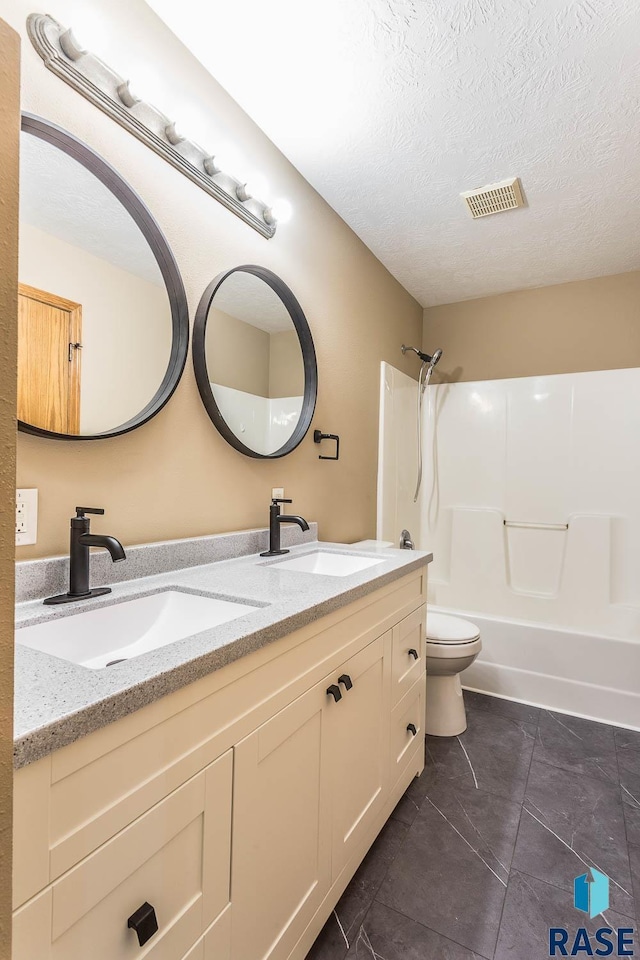 full bathroom featuring tub / shower combination, a textured ceiling, tile patterned floors, vanity, and toilet