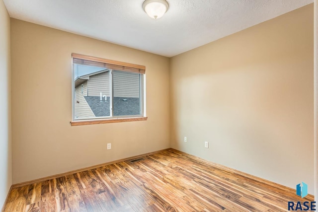 unfurnished room featuring a textured ceiling and light hardwood / wood-style flooring