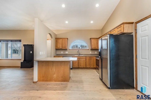 kitchen with appliances with stainless steel finishes, lofted ceiling, sink, kitchen peninsula, and light hardwood / wood-style flooring