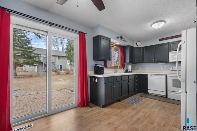 kitchen featuring sink, white appliances, ceiling fan, light hardwood / wood-style floors, and a textured ceiling