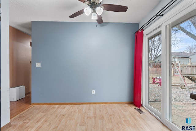 empty room featuring ceiling fan, a textured ceiling, and light hardwood / wood-style flooring