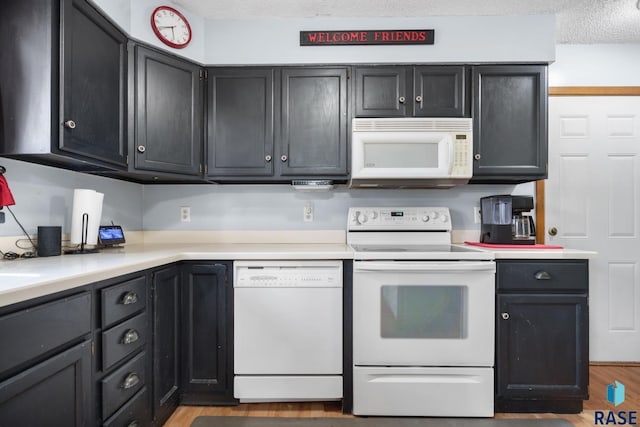 kitchen featuring white appliances, light hardwood / wood-style floors, and a textured ceiling