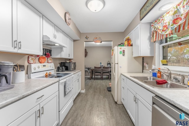 kitchen with white cabinets, light wood-type flooring, sink, and white appliances