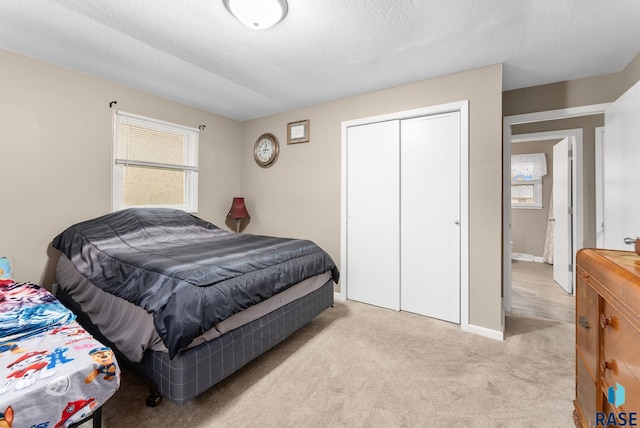 bedroom with a textured ceiling, a closet, and light colored carpet