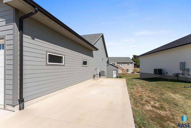 view of side of property with a patio area, cooling unit, and a lawn