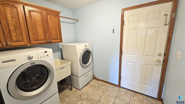 washroom featuring washing machine and dryer, cabinets, and light tile patterned floors