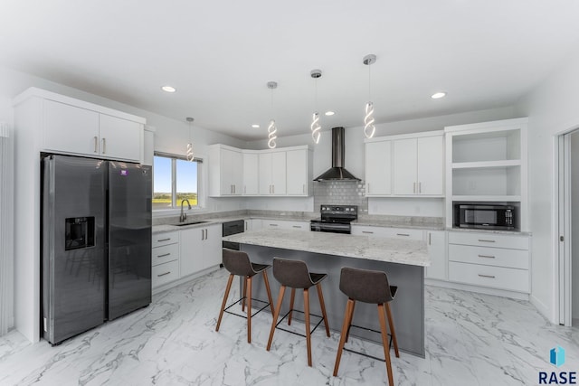 kitchen with wall chimney exhaust hood, white cabinets, a center island, and black appliances