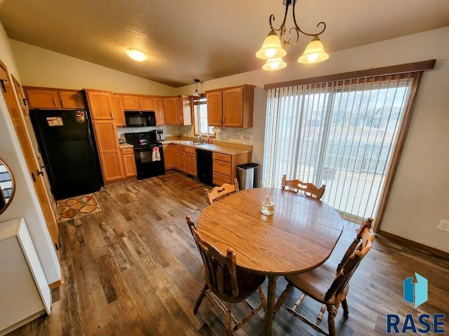 dining room with lofted ceiling, wood-type flooring, a notable chandelier, and sink